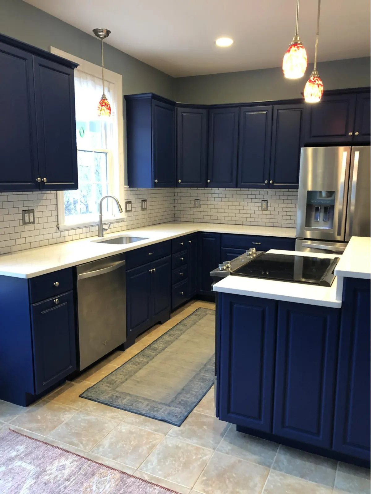 Kitchen remodel with blue cabinets, white countertops, and island cooktop