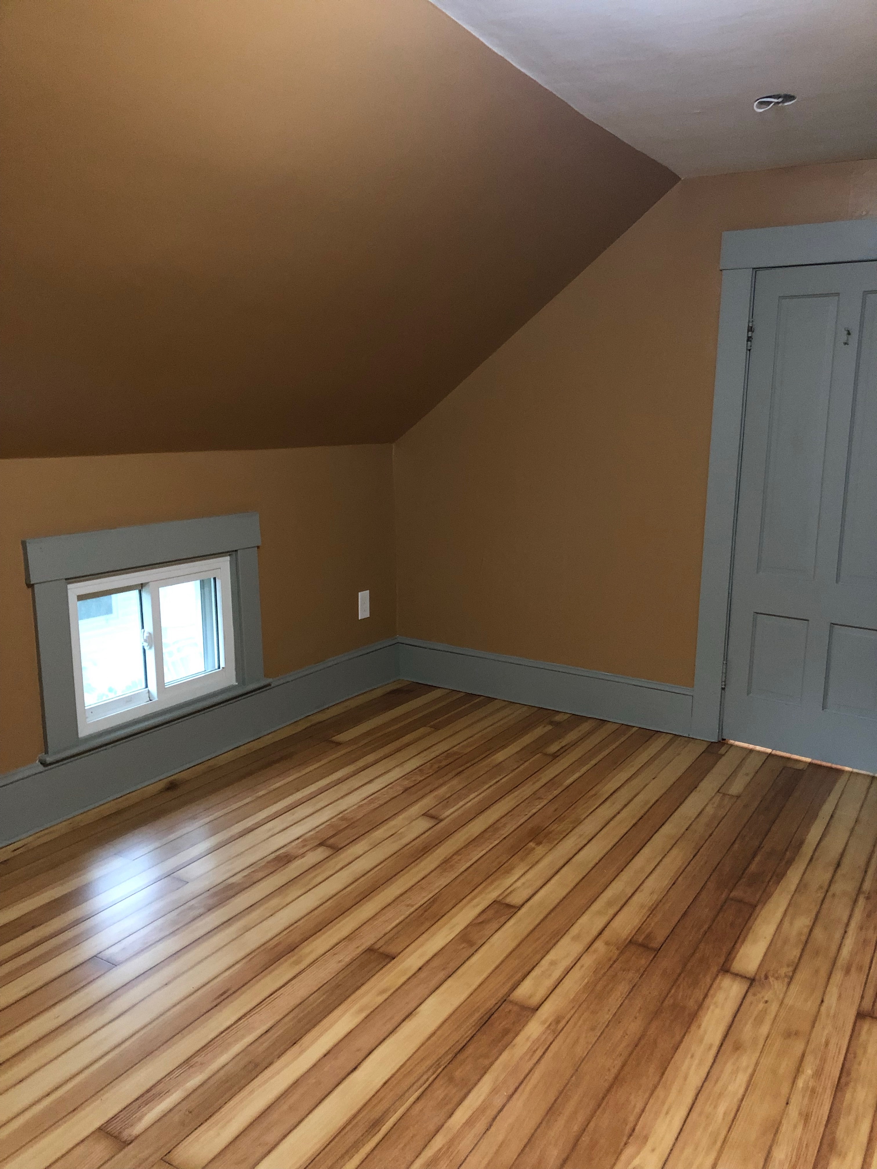 Finished attic room with sloped ceiling and refinished hardwood floors