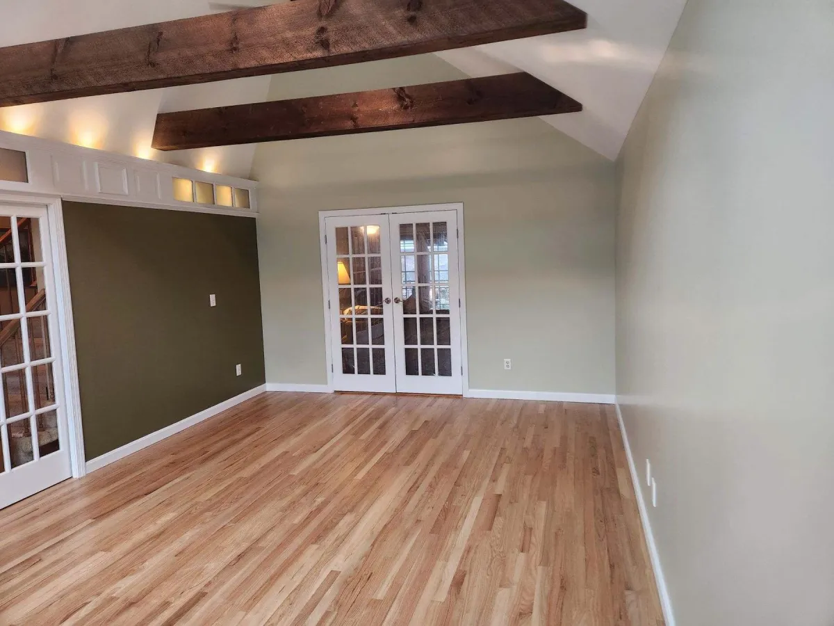 Finished room with hardwood floors, exposed ceiling beams, and french doors