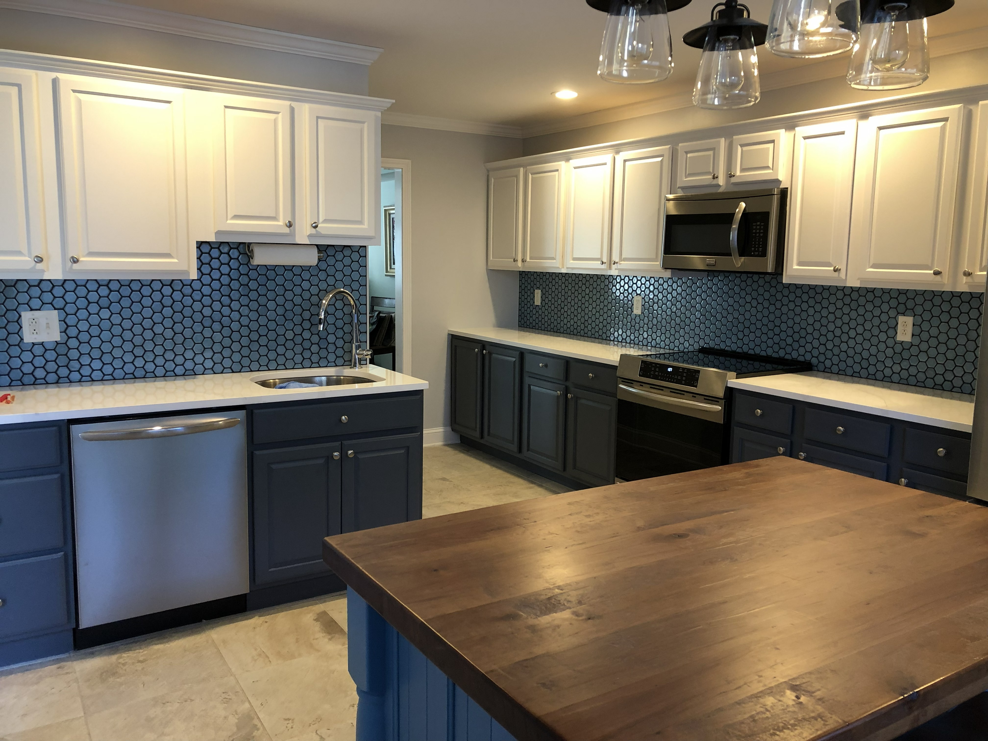 Kitchen remodel with blue cabinets, white uppers, and hex tile backsplash