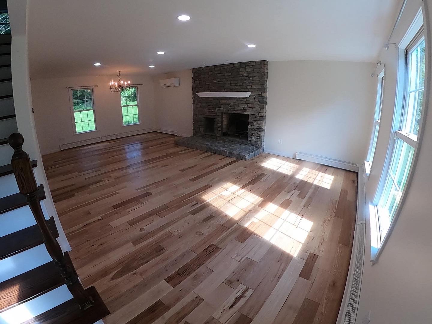 Renovated living room with hardwood floors and stone fireplace feature