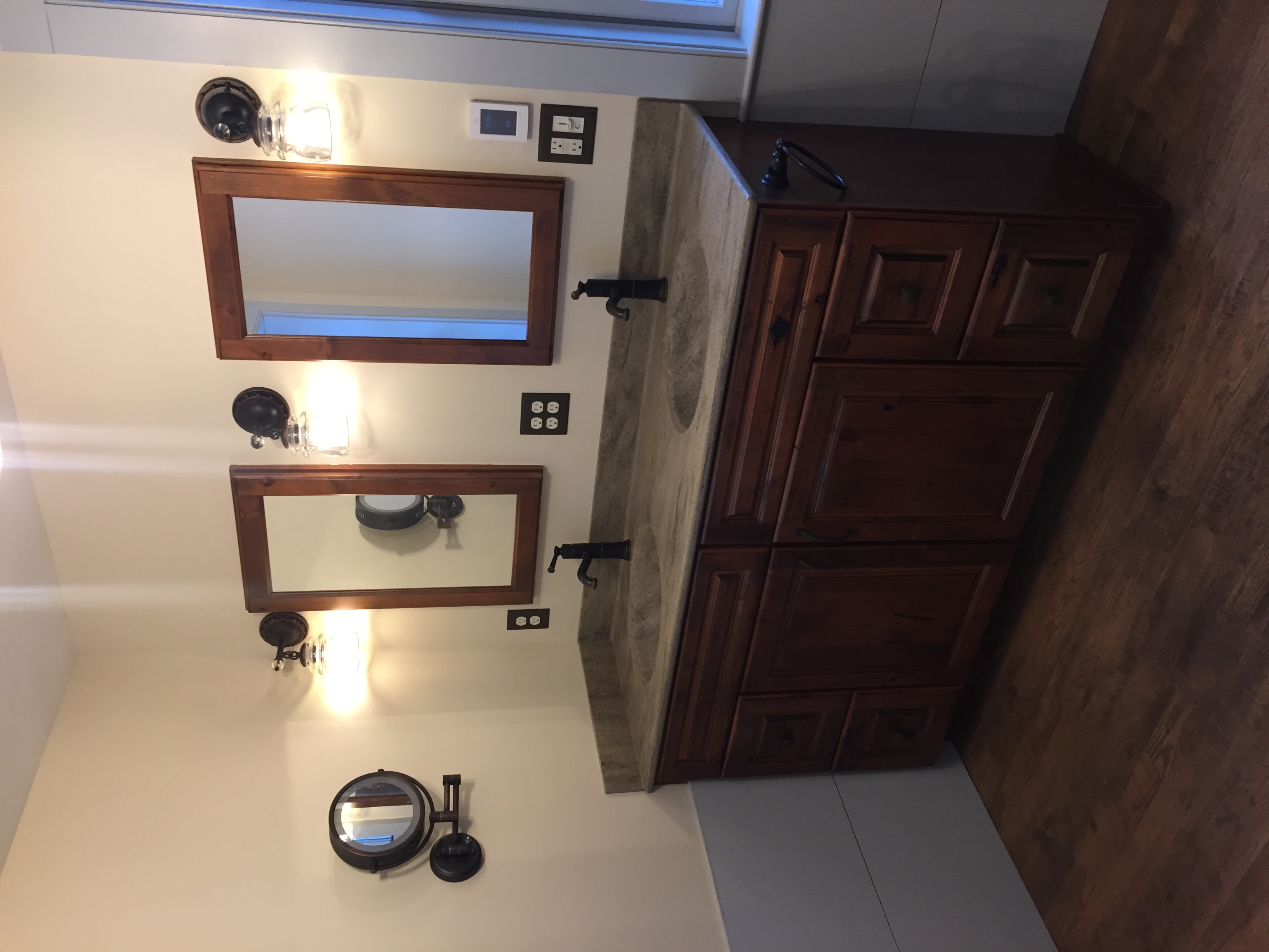 Bathroom remodel with double sink vanity, wood cabinets, and wall-mounted mirrors