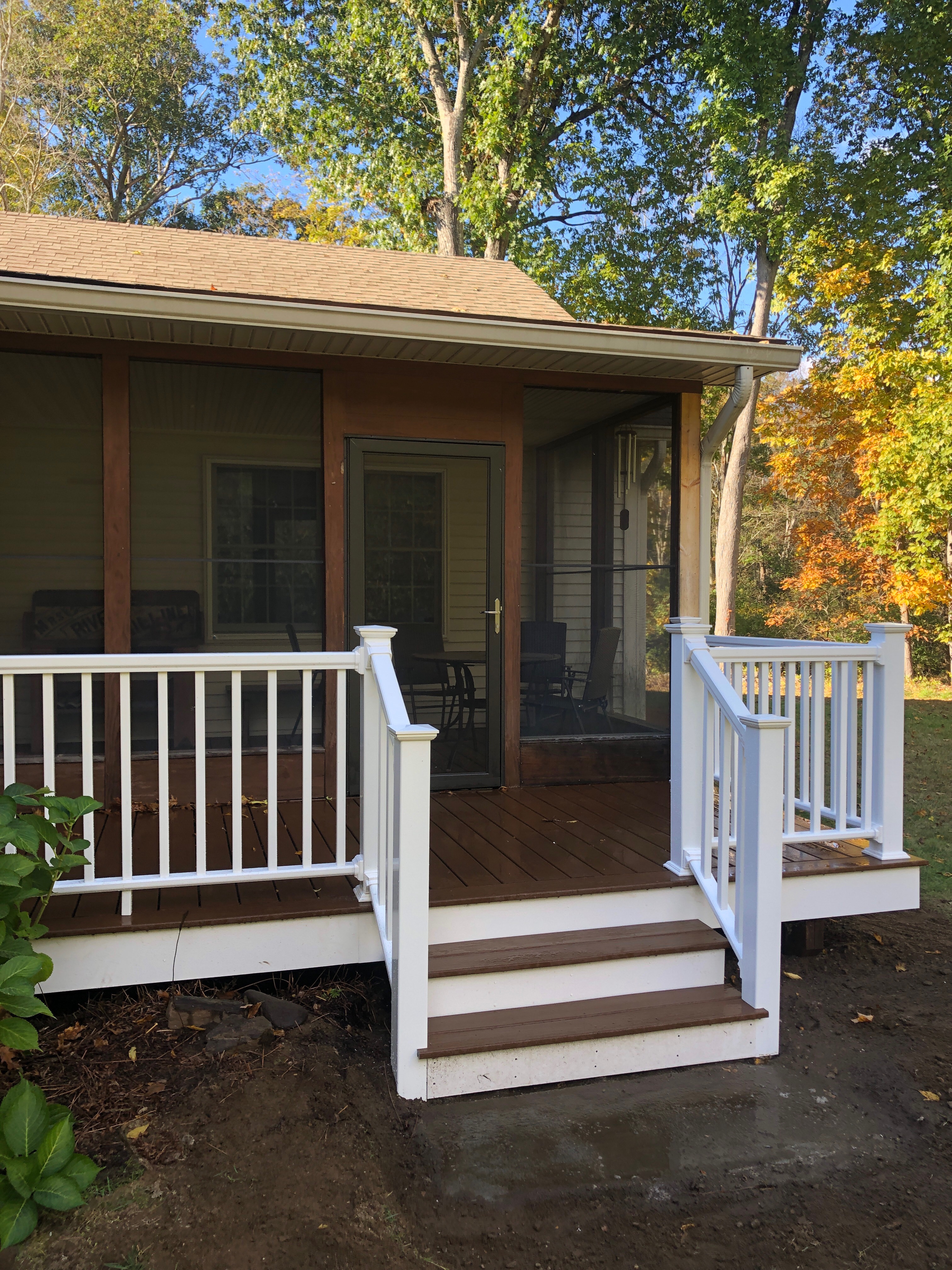 Backyard deck with white railing and screened porch addition