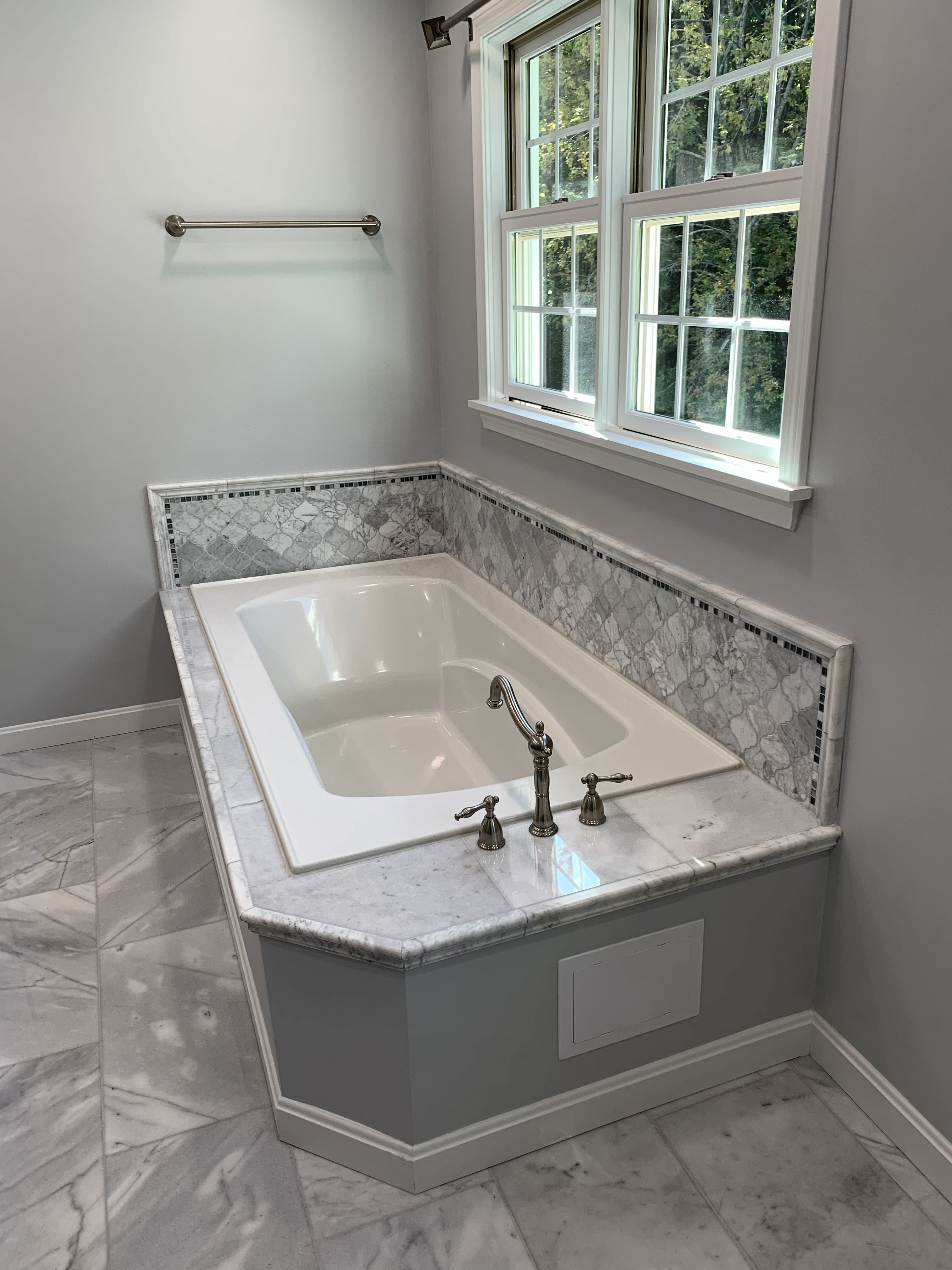 Built-in soaking bathtub with marble surround and window above