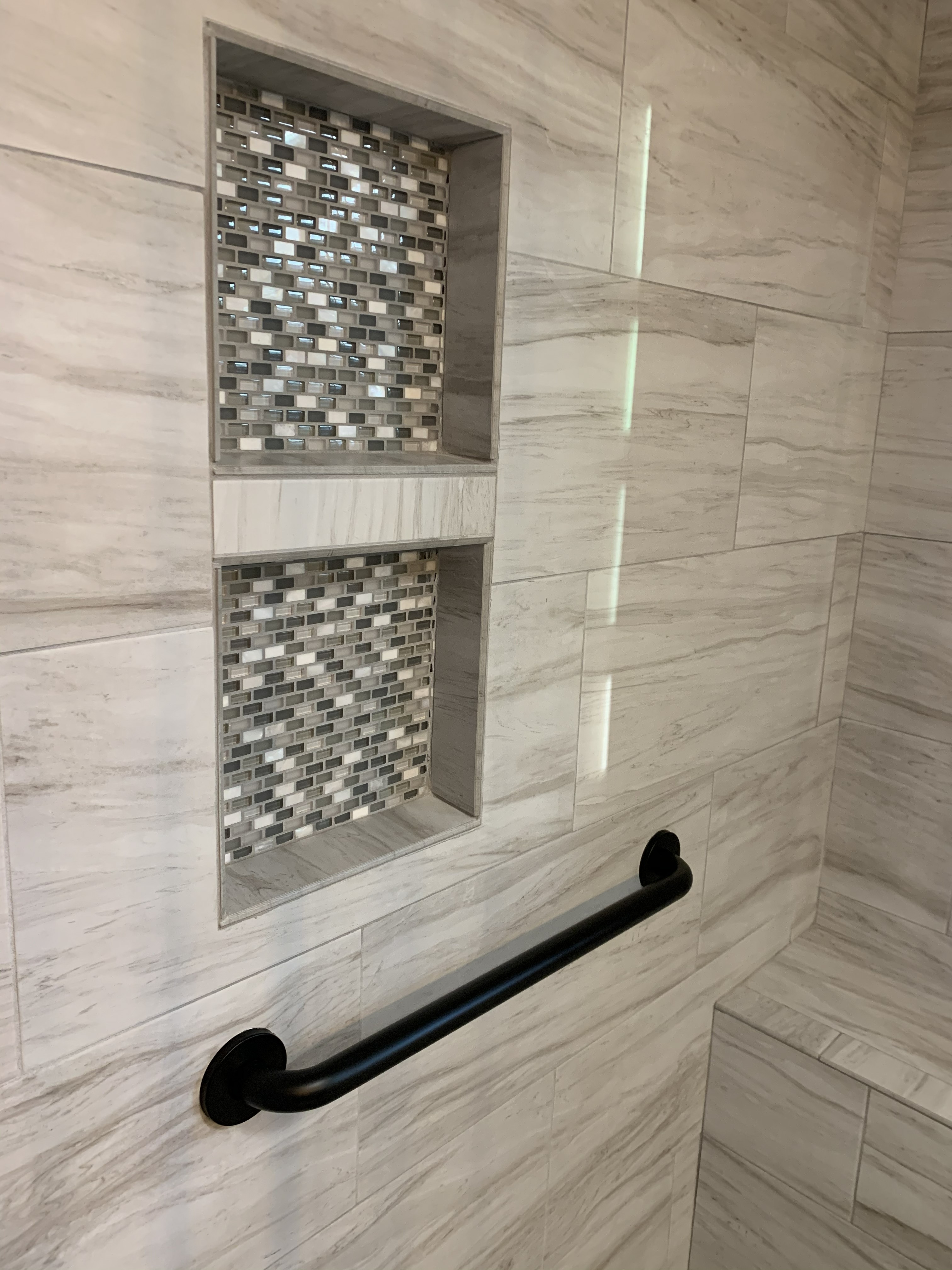 Tiled shower wall with recessed storage niches and grab bar