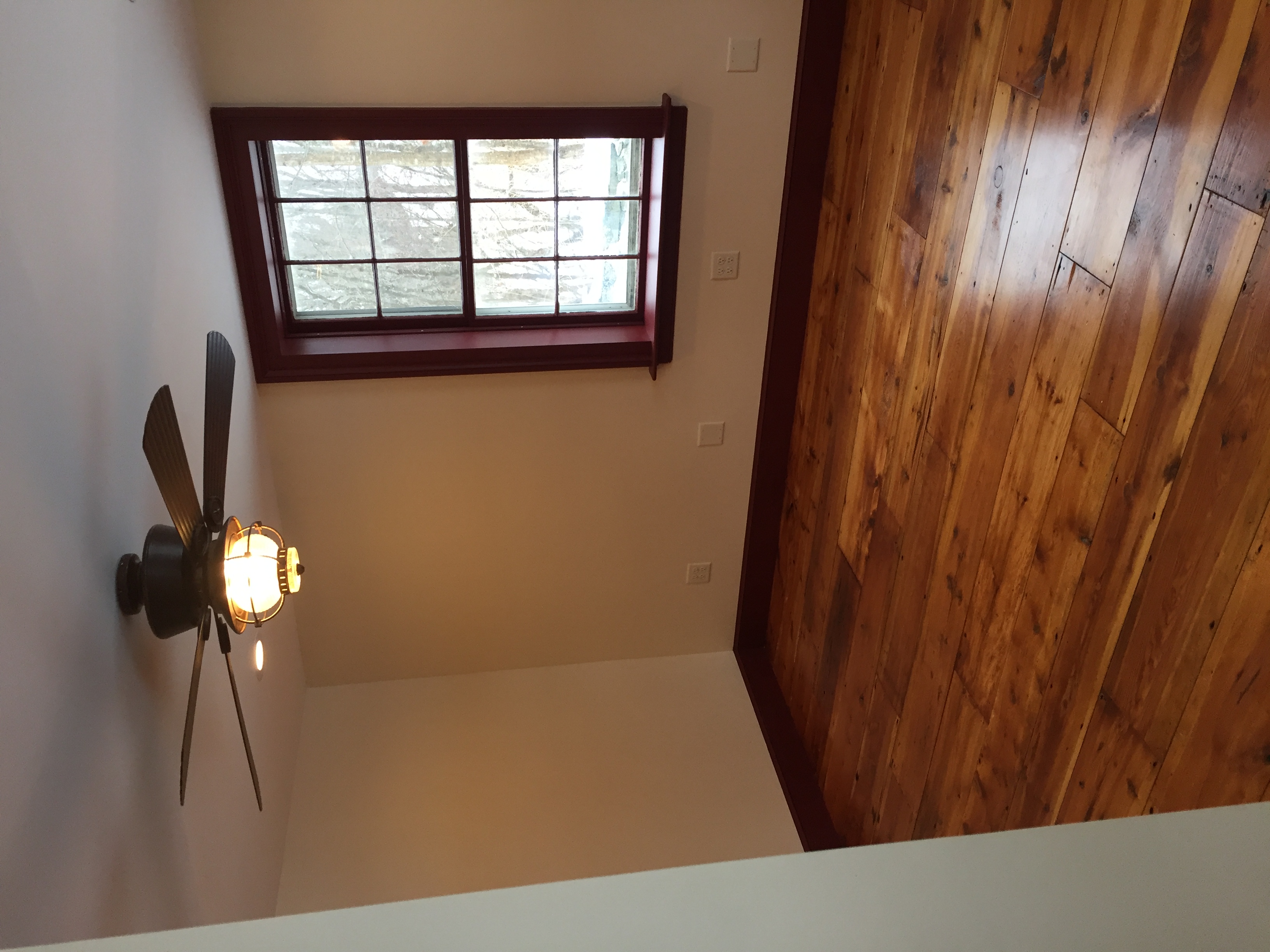 Hardwood floor installation in room with ceiling fan and window