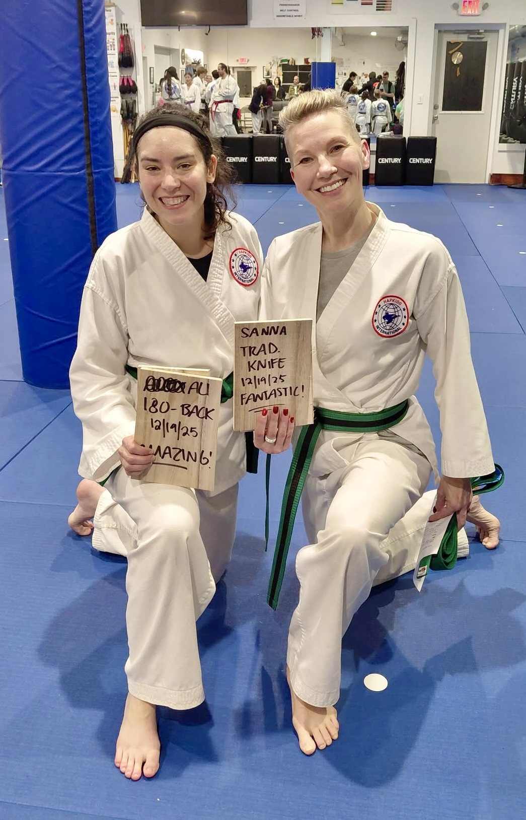 A young woman practicing Hapkido kicks in her living room, following an online class on a laptop.