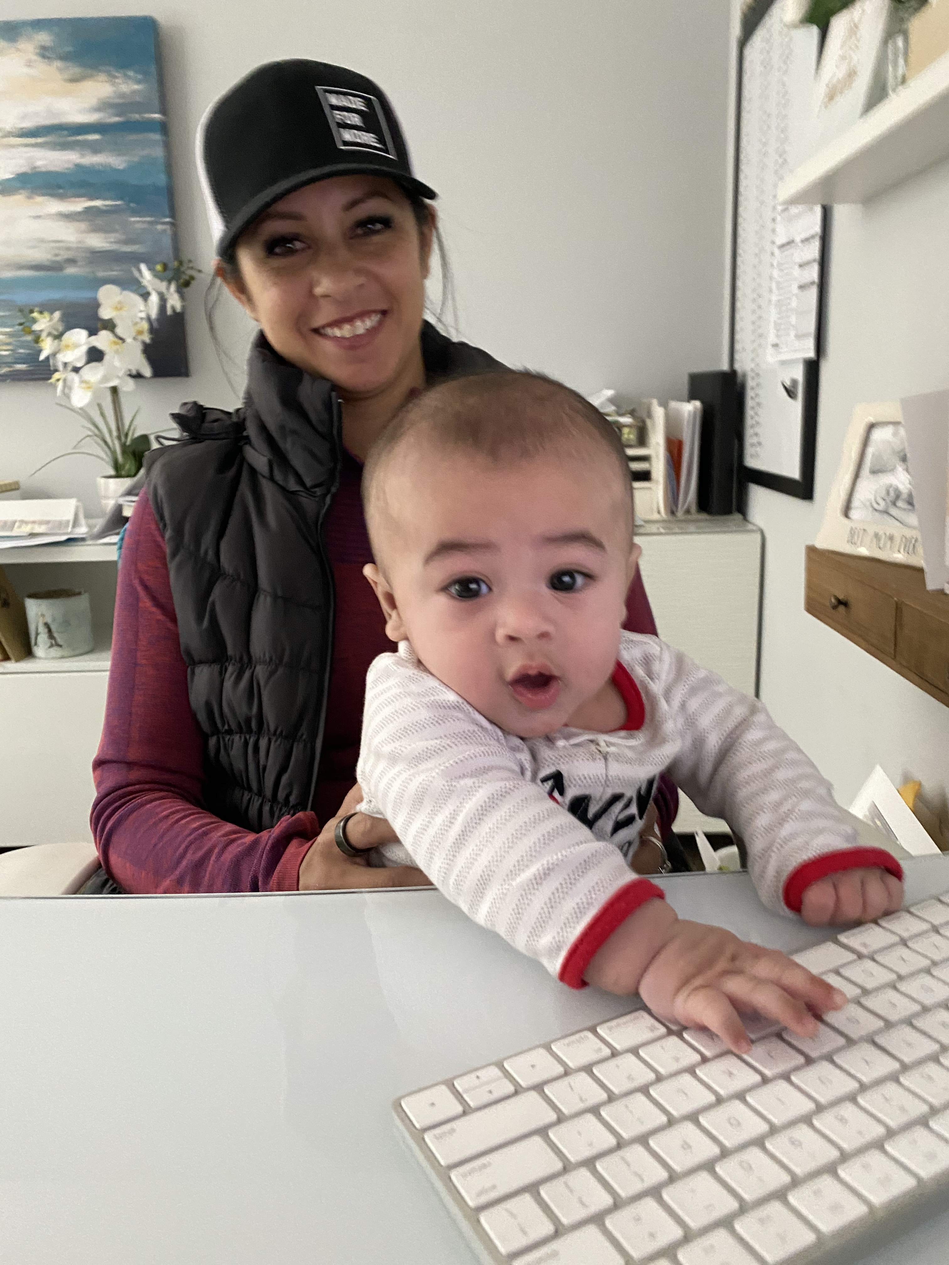 A smiling mom and her young son sit together at a kitchen table, both looking at a colorful laptop screen. Sunlight streams in, highlighting their joyful faces. The background is softly blurred, emphasizing their close bond and shared excitement for learning.