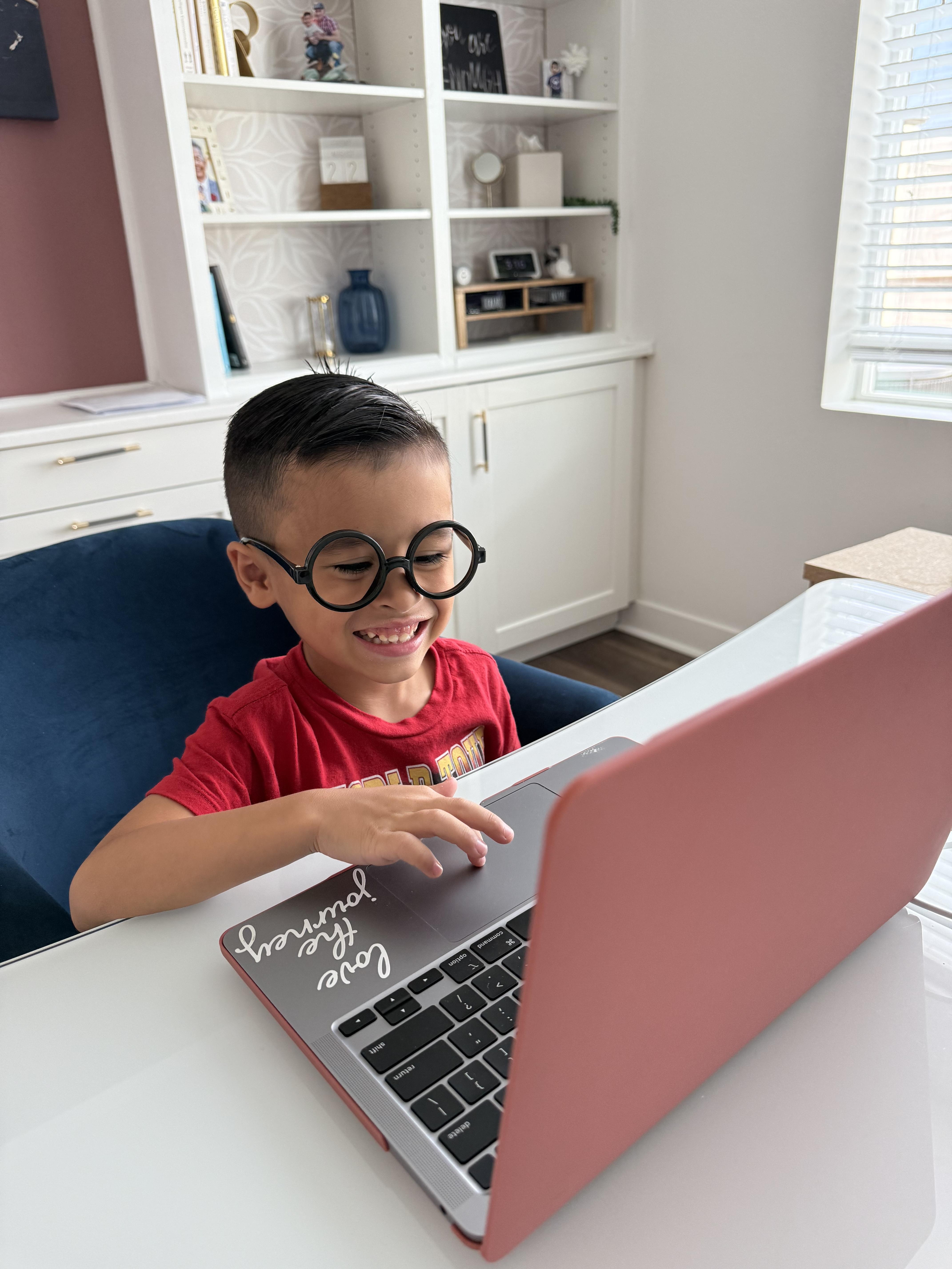 a young boy wearing glasses working on the compter