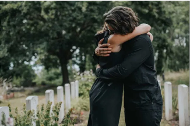 A man and woman hugging in a cemetery, perhaps reflecting on the emotional journey of probate administration or trust settlement.