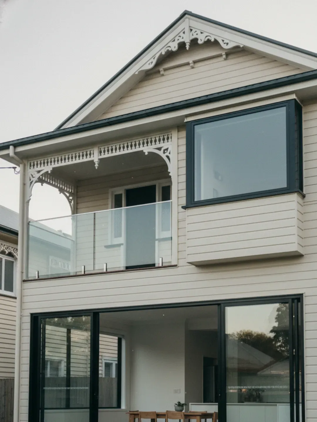 Family-owned Ascot glazier story with work ute and safely supported glass panel outside a Queenslander home.