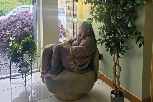 Julie, resting on her chair. Warm, real, in the act of settling rather than posed as already calm.