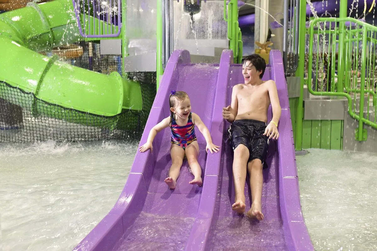 Kids going down the slides at the aquatic indoor playground in Chaos Water Park
