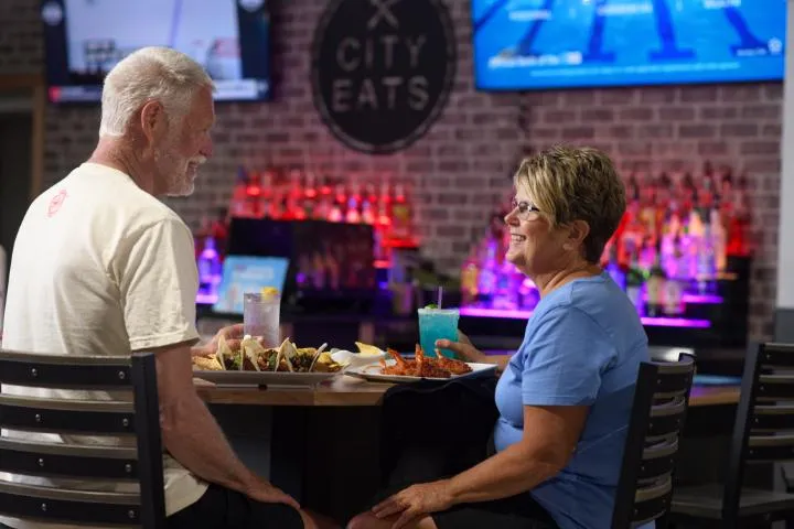 A couple eating and drinking at the City Eats bar in Action City