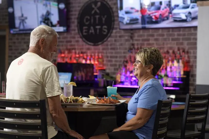 A couple eating and drinking at the bar in City Eats