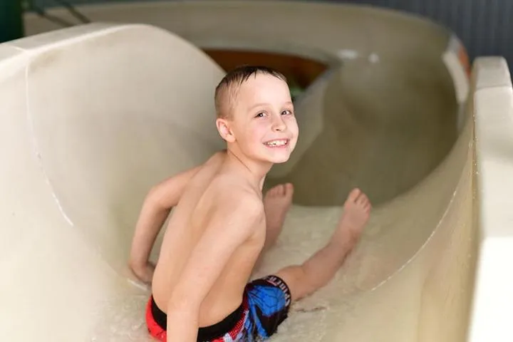 A boy sitting at the top of the Twister Water Slide in Chaos Water Park