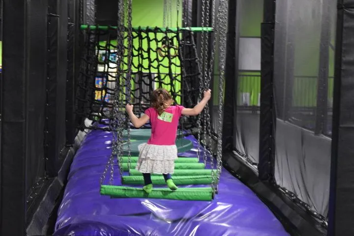 A kid playing on the ninja warrior course in the trampoline park at Action City