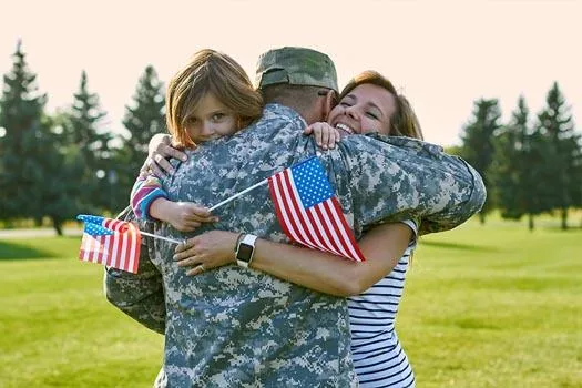 A veteran hugging his wife and daughter