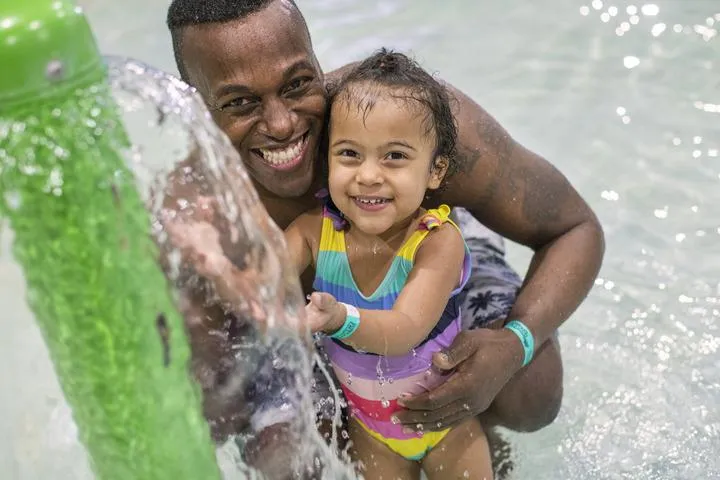 A dad and daughter playing in the indoor aquatic playground at Chaos Water Park