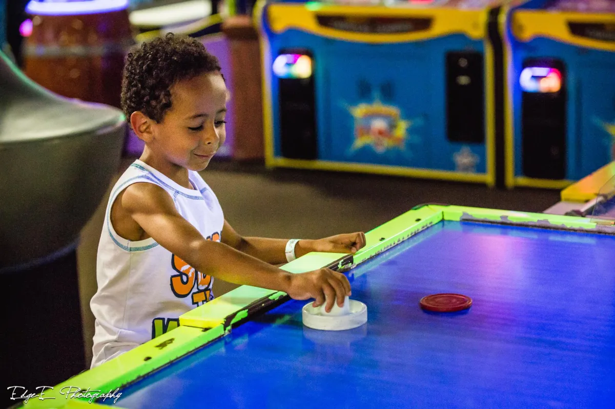 A kid playing air hockey in Action City