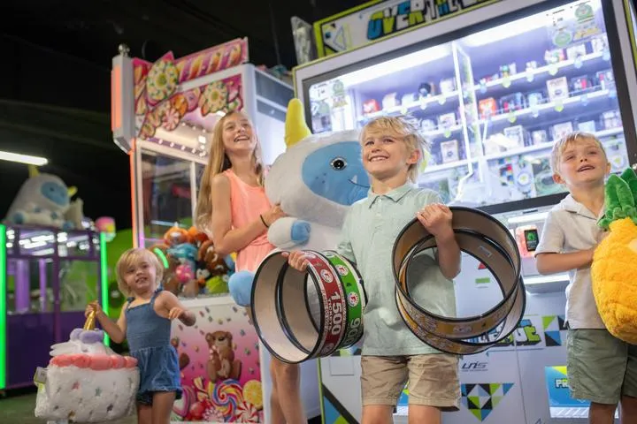 Kids holding tickets and prizes in the Action City arcade
