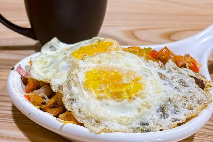 City Eats Chorizo Skillet with eggs over breakfast potatoes, peppers, onions, tomatoes, chorizo, cheddar cheese, and cilantro.