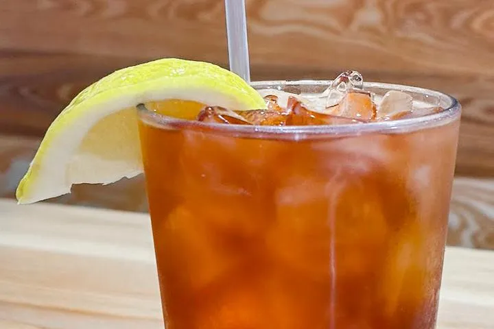 City Eats Blackberry Arnold Palmer cocktail with Crown Royal Blackberry, lemonade, unsweetened tea, garnished with a lemon.