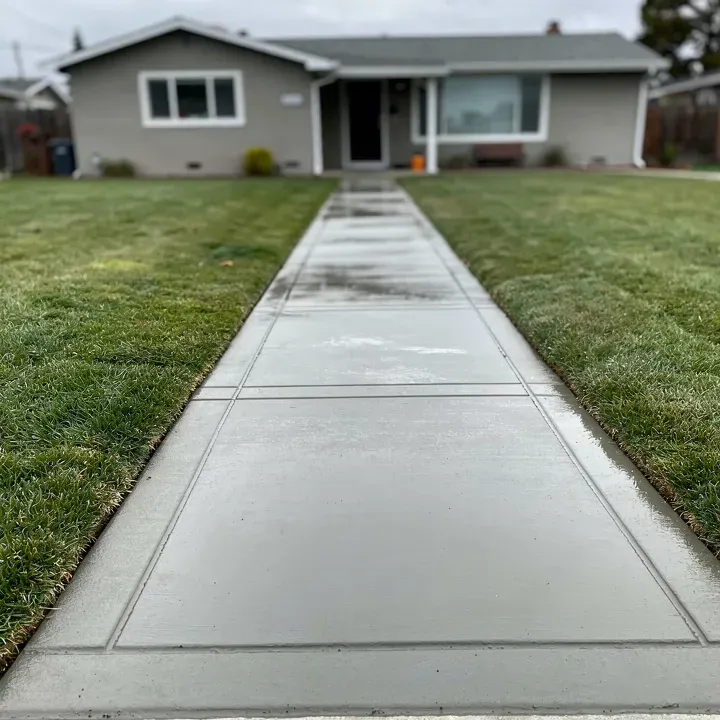 Freshly finished concrete sidewalk with control joints alongside a home in Redwood City, California