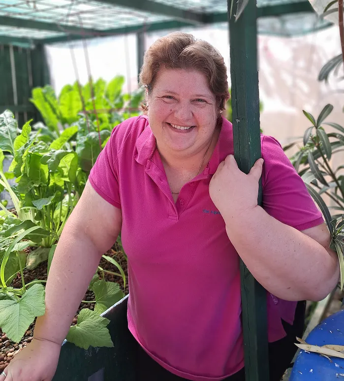 Candy Alexander beside a productive backyard aquaponics system.