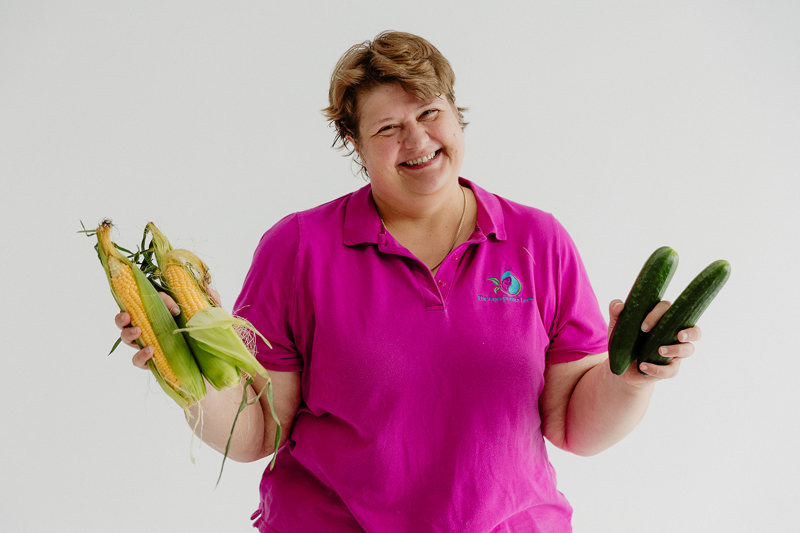 Candy Alexander smiling while holding freshly harvested cucumbers.