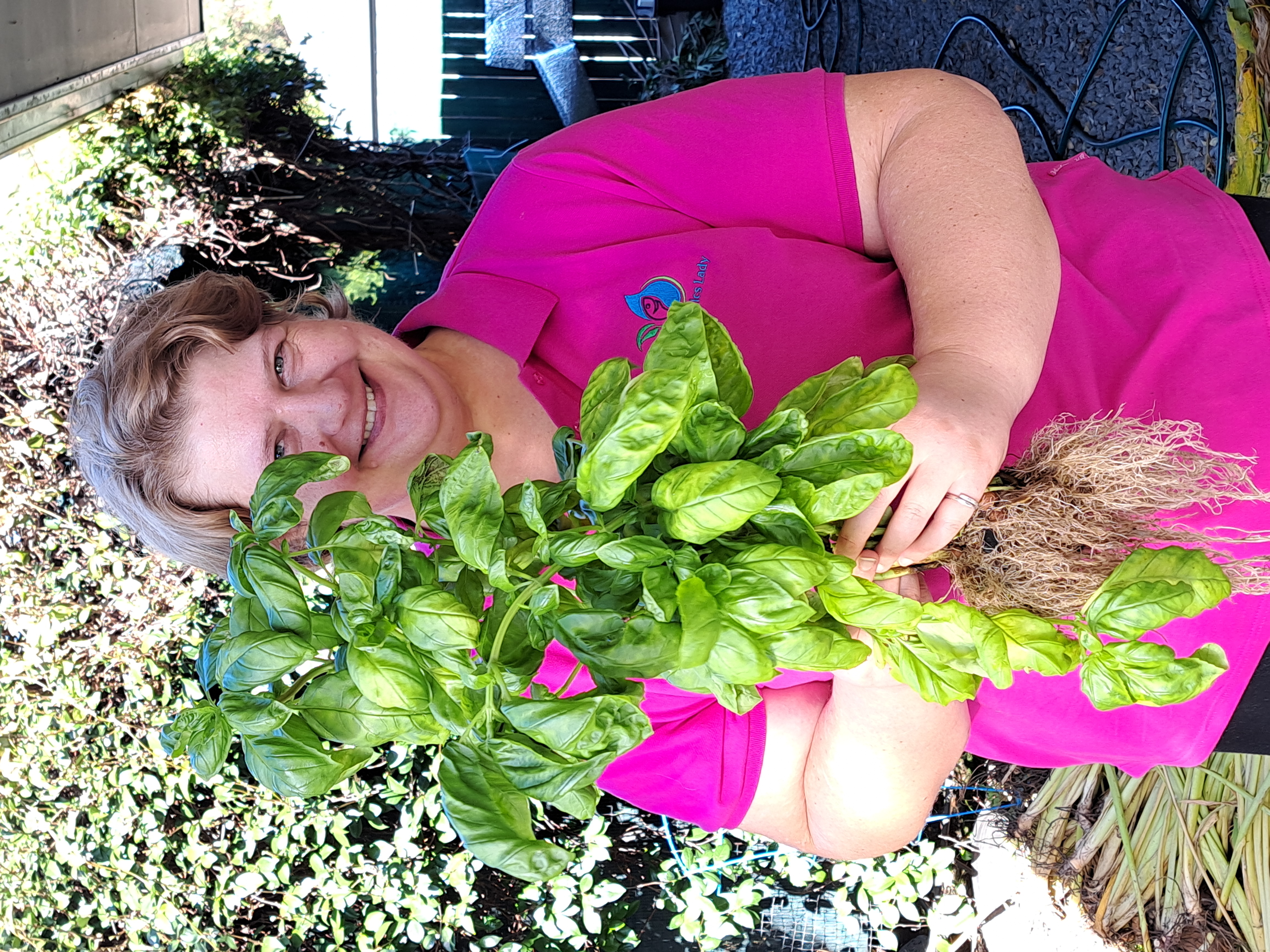 Candy holding freshly harvested basil grown in an aquaponics herb garden.