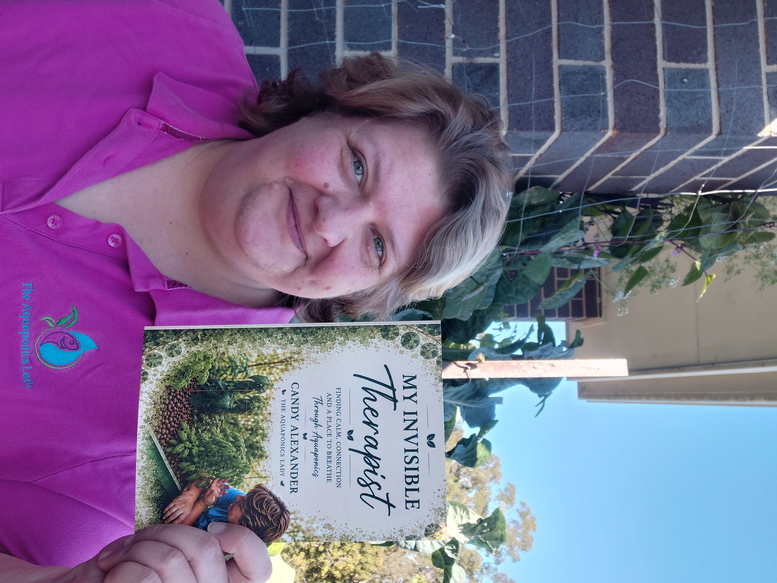 Candy Alexander The Aquaponics Lady holding her book My Invisible Therapist about aquaponics and personal recovery