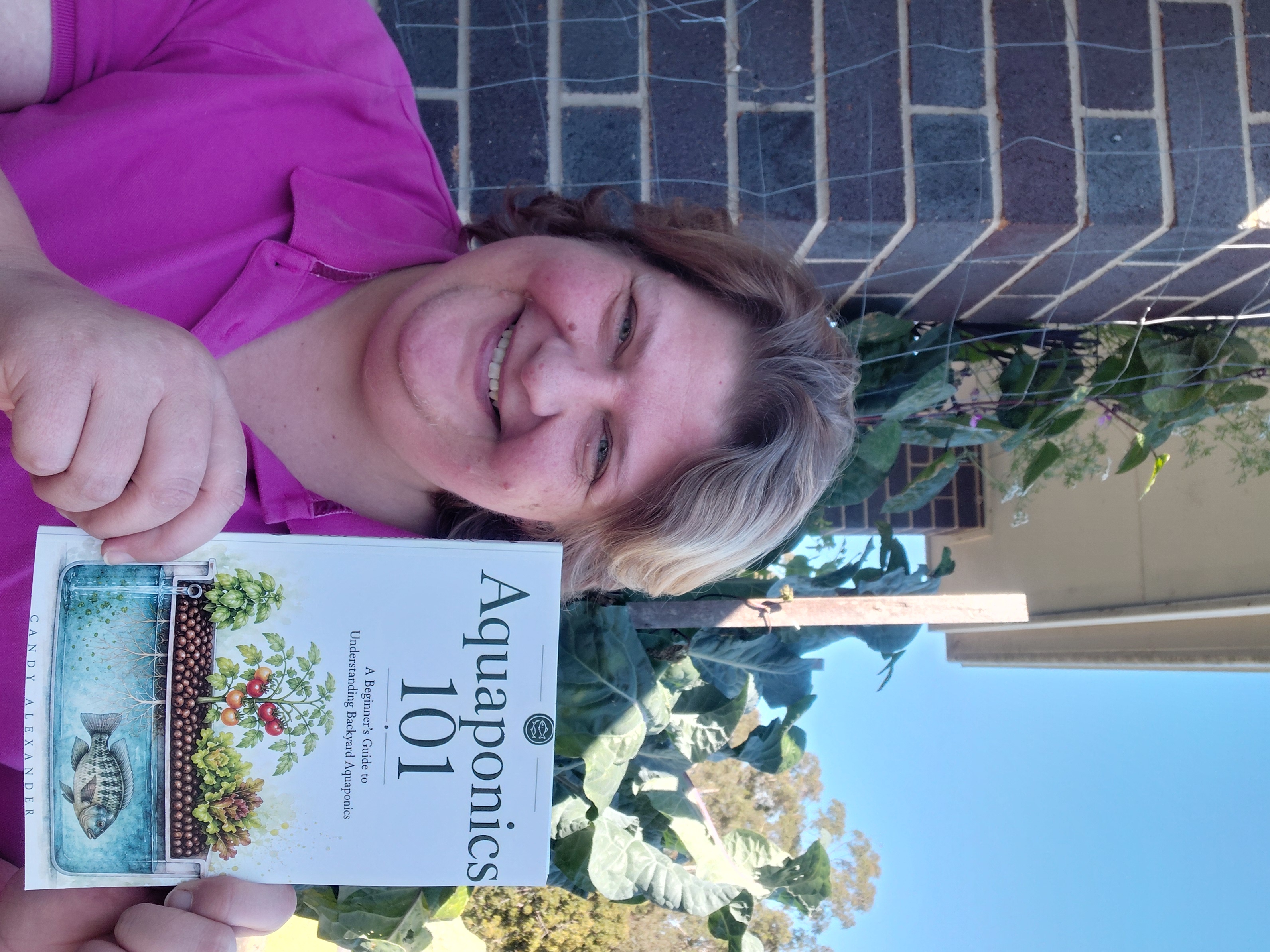 Candy Alexander, The Aquaponics Lady, holding her Aquaponics 101 beginner aquaponics book.