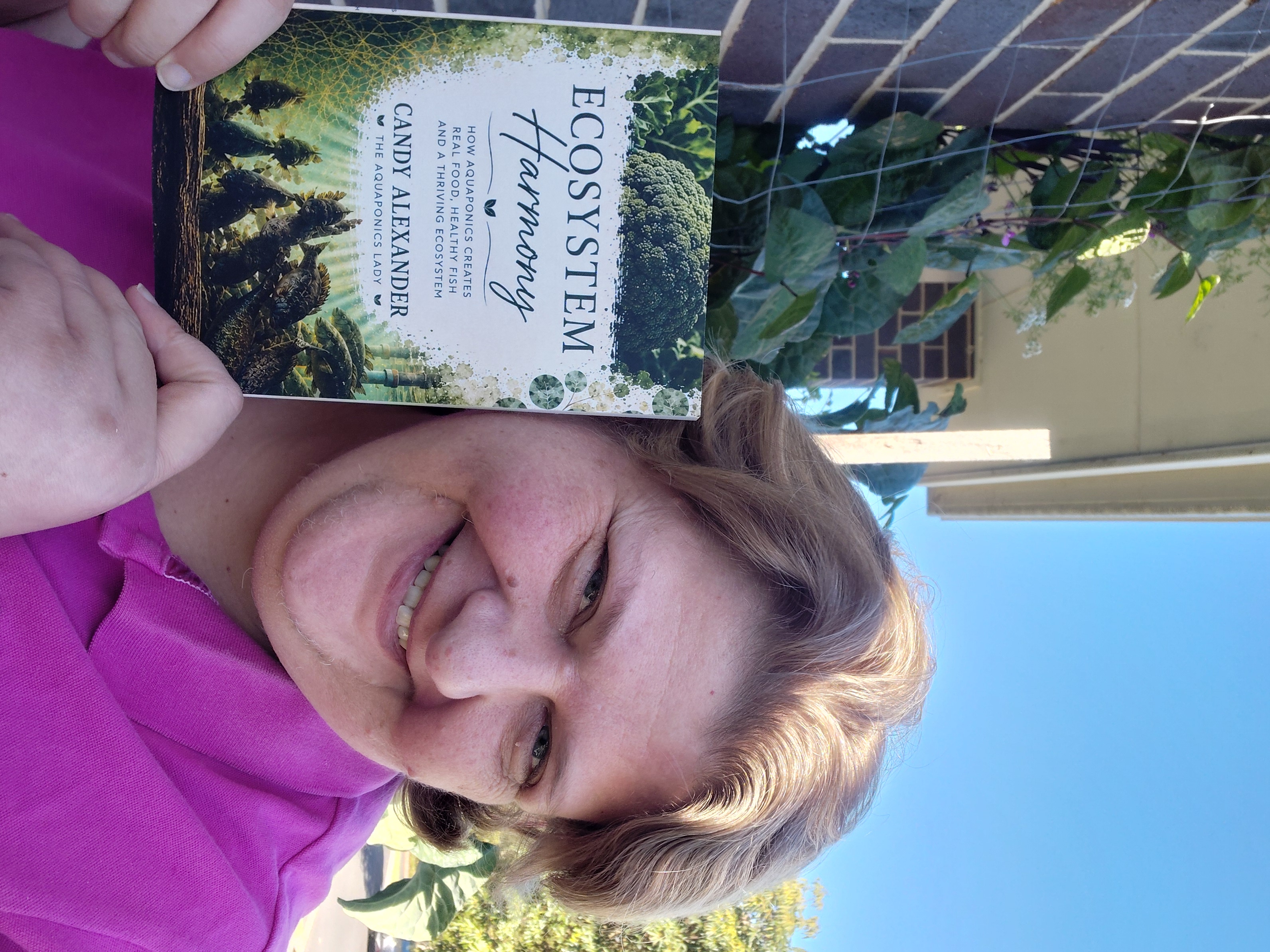 Candy Alexander, The Aquaponics Lady, holding her Ecosystem Harmony aquaponics book.