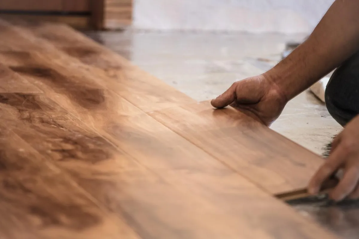Professional flooring installer laying planks during installation