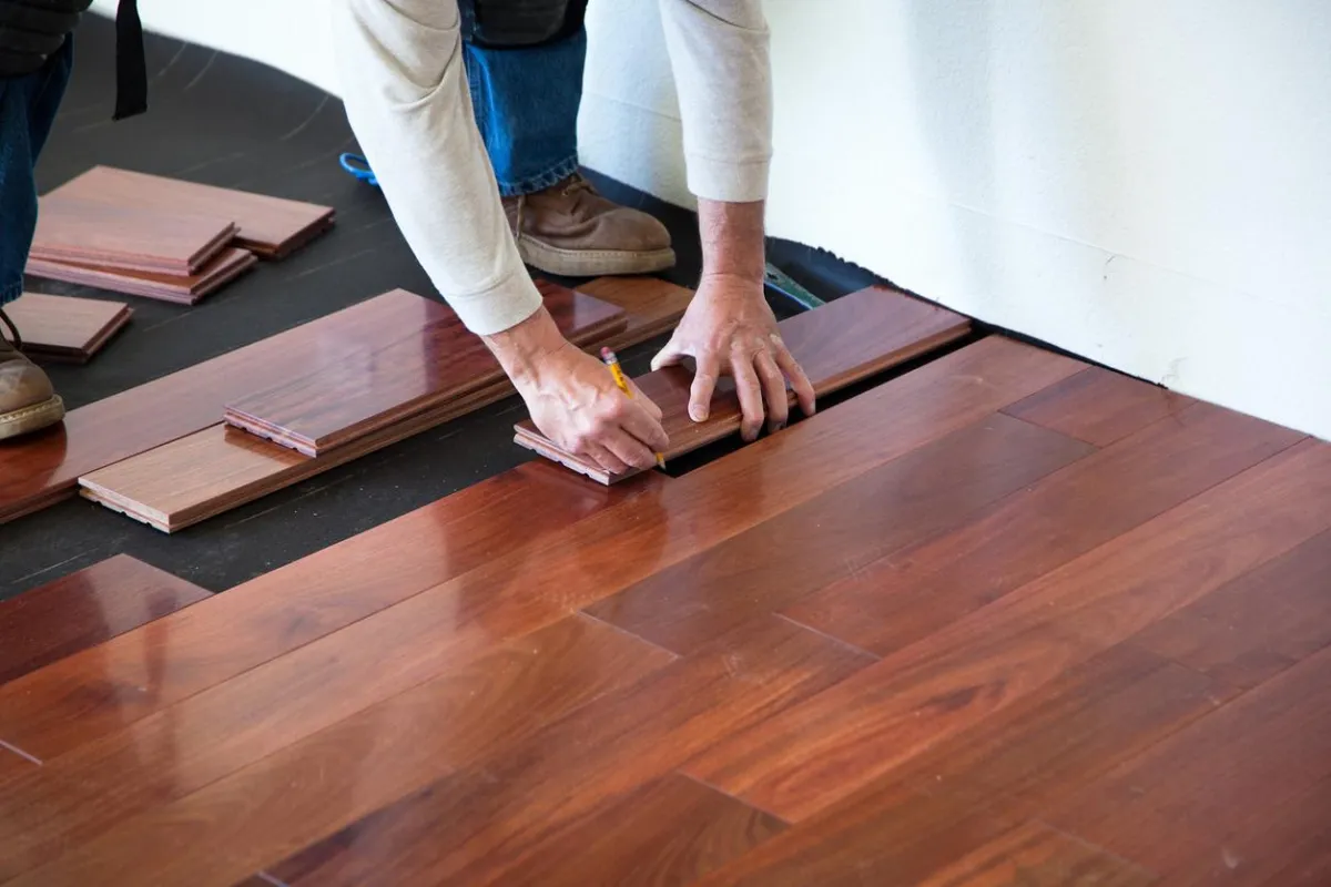 Professional installer fitting hardwood floor planks
