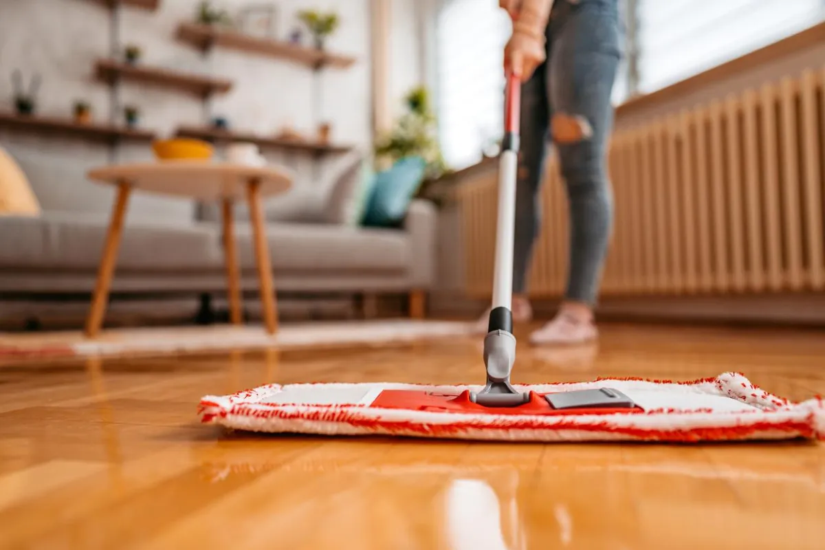 Homeowner cleaning laminate floor to maintain shine and durability