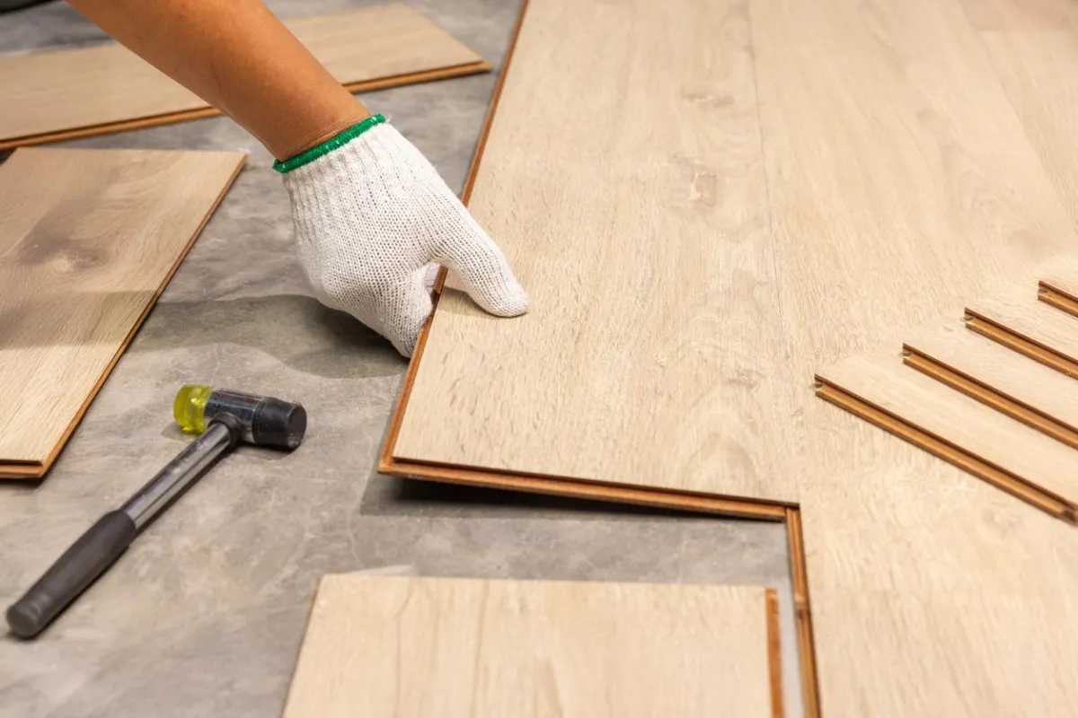 Worker fitting laminate planks together for flooring installation