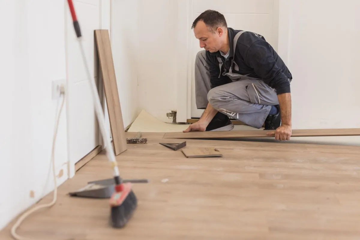 Man installing hardwood floor panels during home renovation