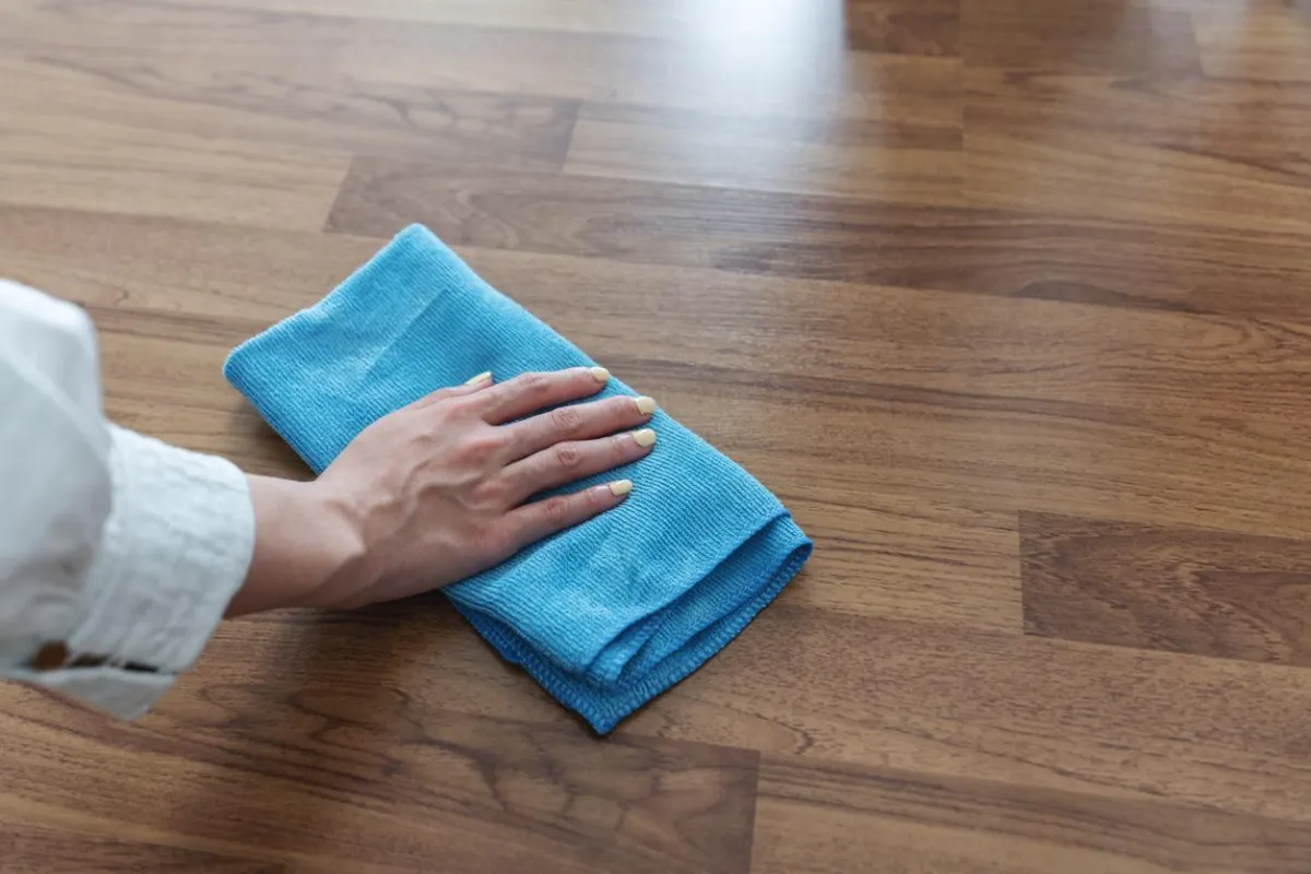 Person wiping laminate floor to maintain cleanliness and protect surface
