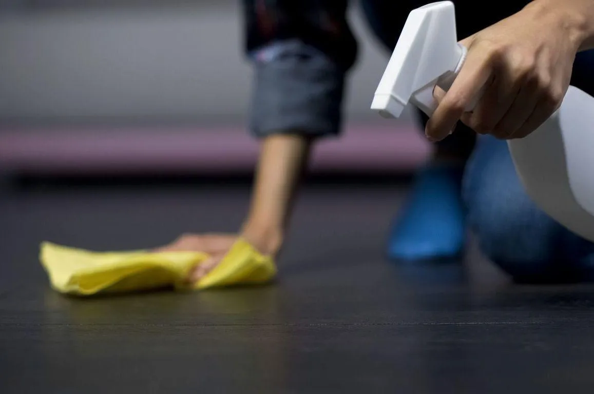 Hand wiping and cleaning stains off a vinyl floor with cloth for maintenance