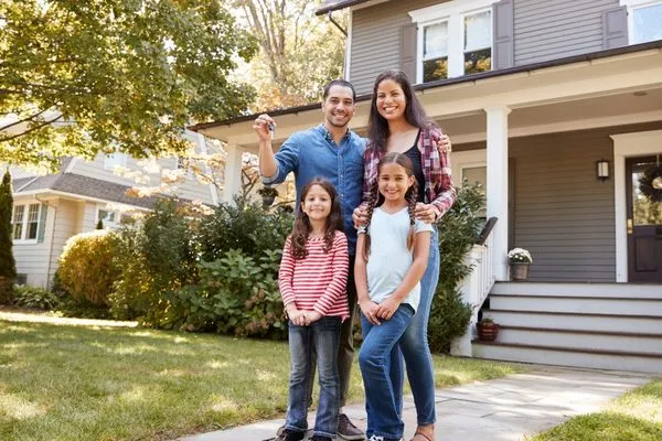Family holding the keys in front of their new home