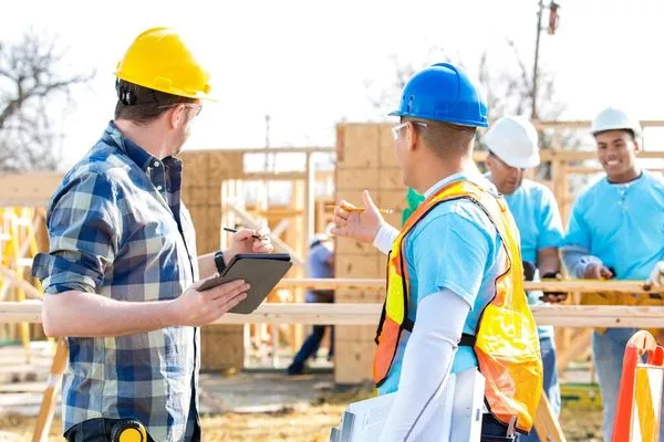 Builders reviewing plans at a home construction site