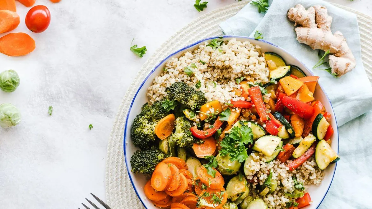 A bowl of nourishing vegetables and quinoa on a pale background