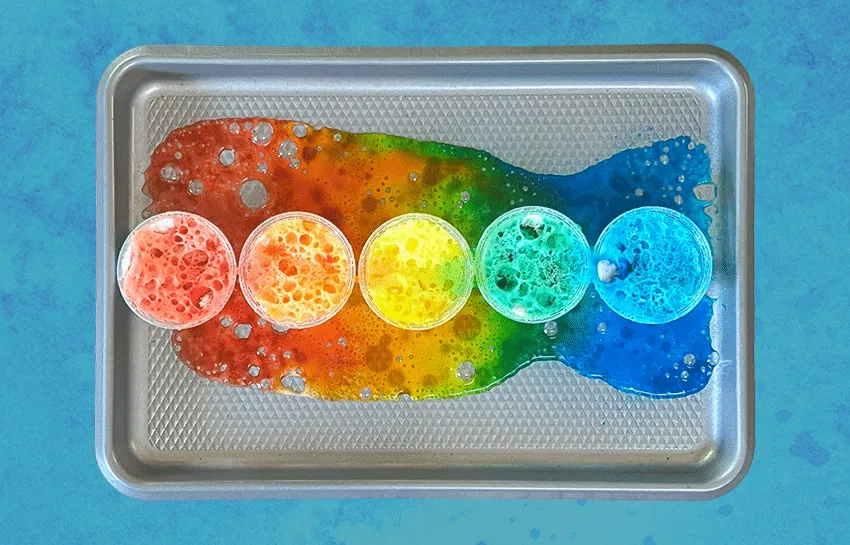 Boy picks paper out of different colored liquids