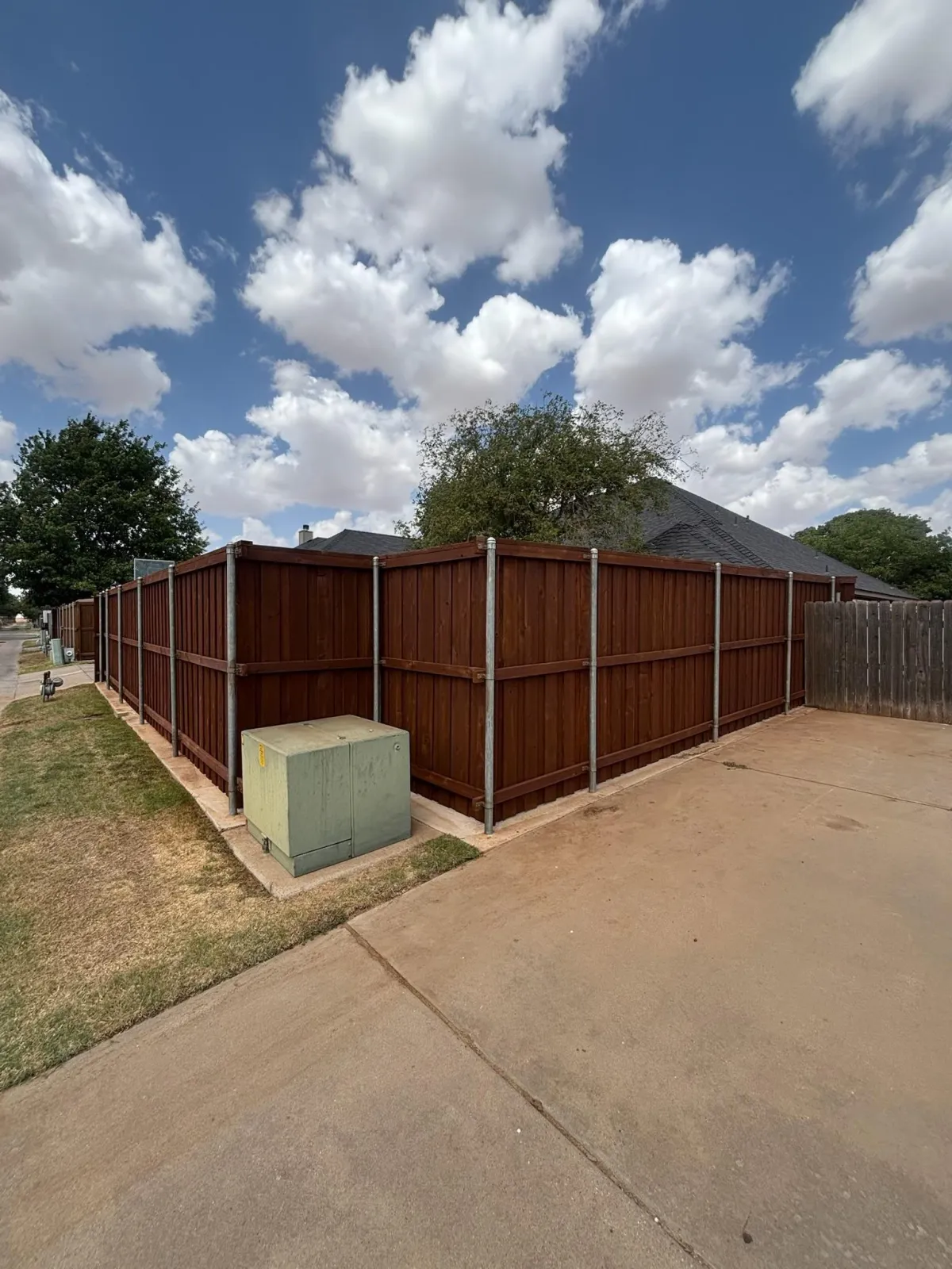 Dark stained wood fence along a gravel side yard in Lubbock, TX