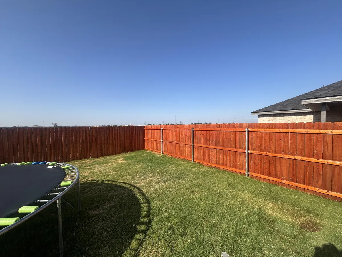 Freshly stained wood fence along a driveway in Lubbock, TX