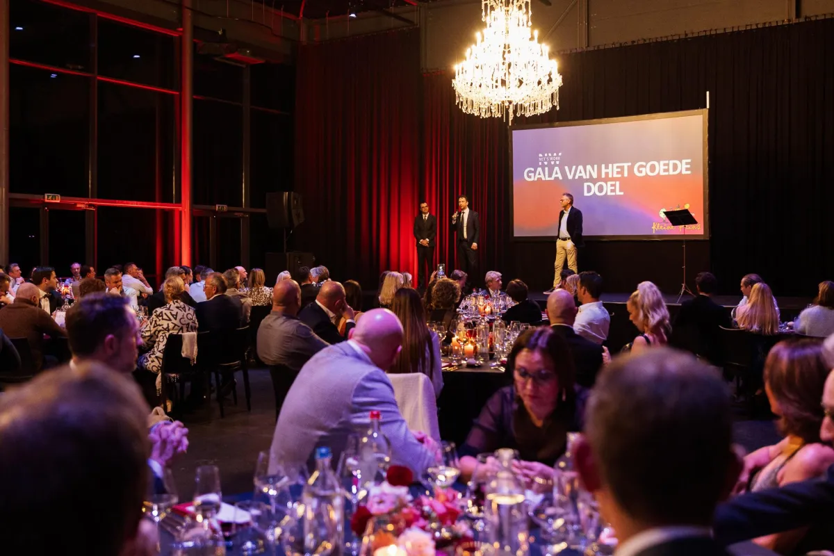 Formeel gala met lange tafel, warme verlichting en gasten in gesprek