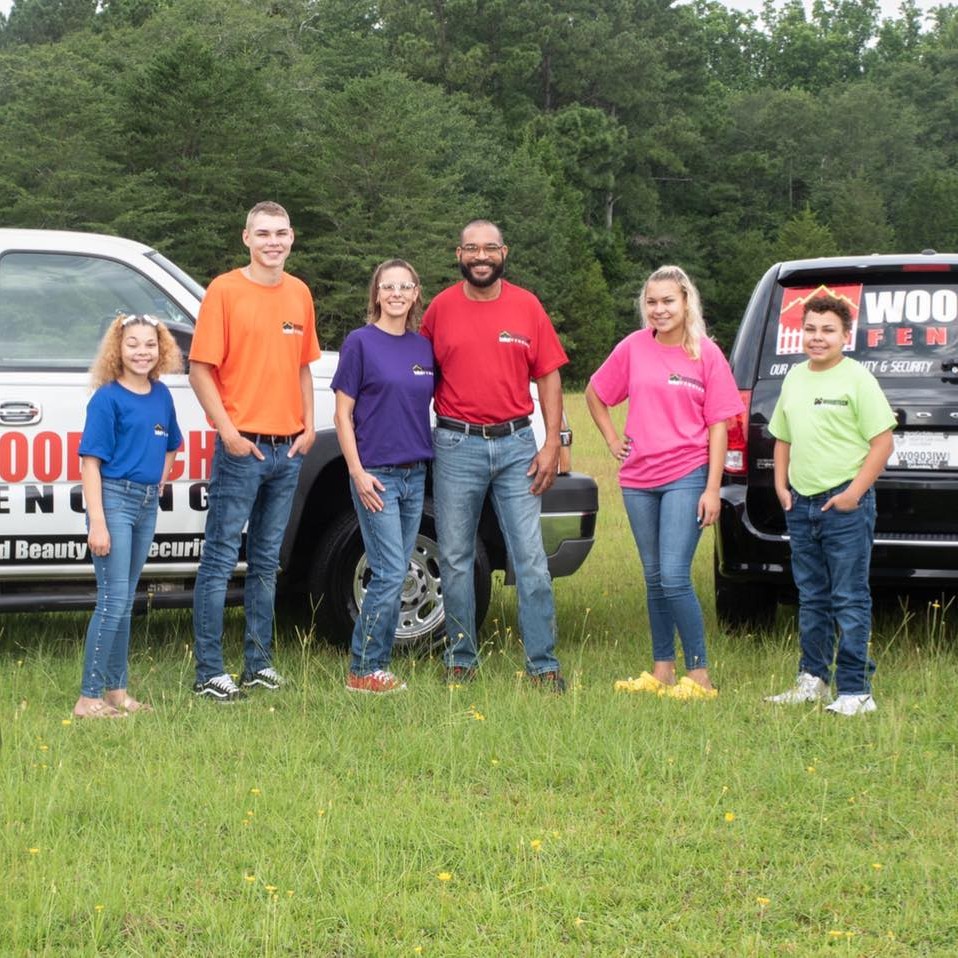 A wooden fence in front of a lush green field