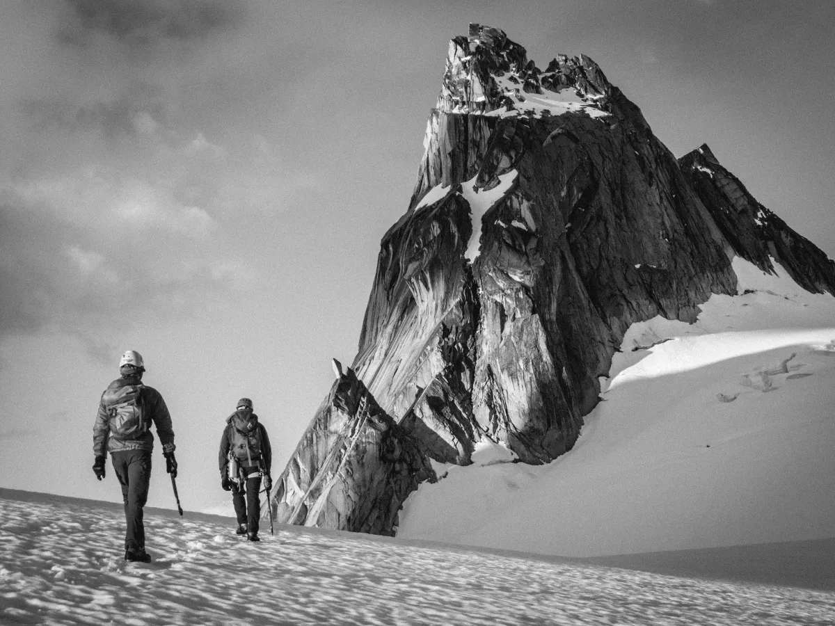 Two people walking towards a mountain